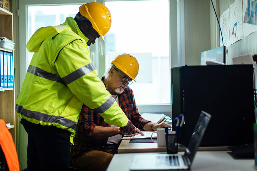 insights3 two men in hardhats inside of an office looking at data
